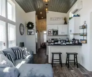 Living Room with small kitchen incredible tiny home model Joann made by Pratt Homes, Tyler, Texas